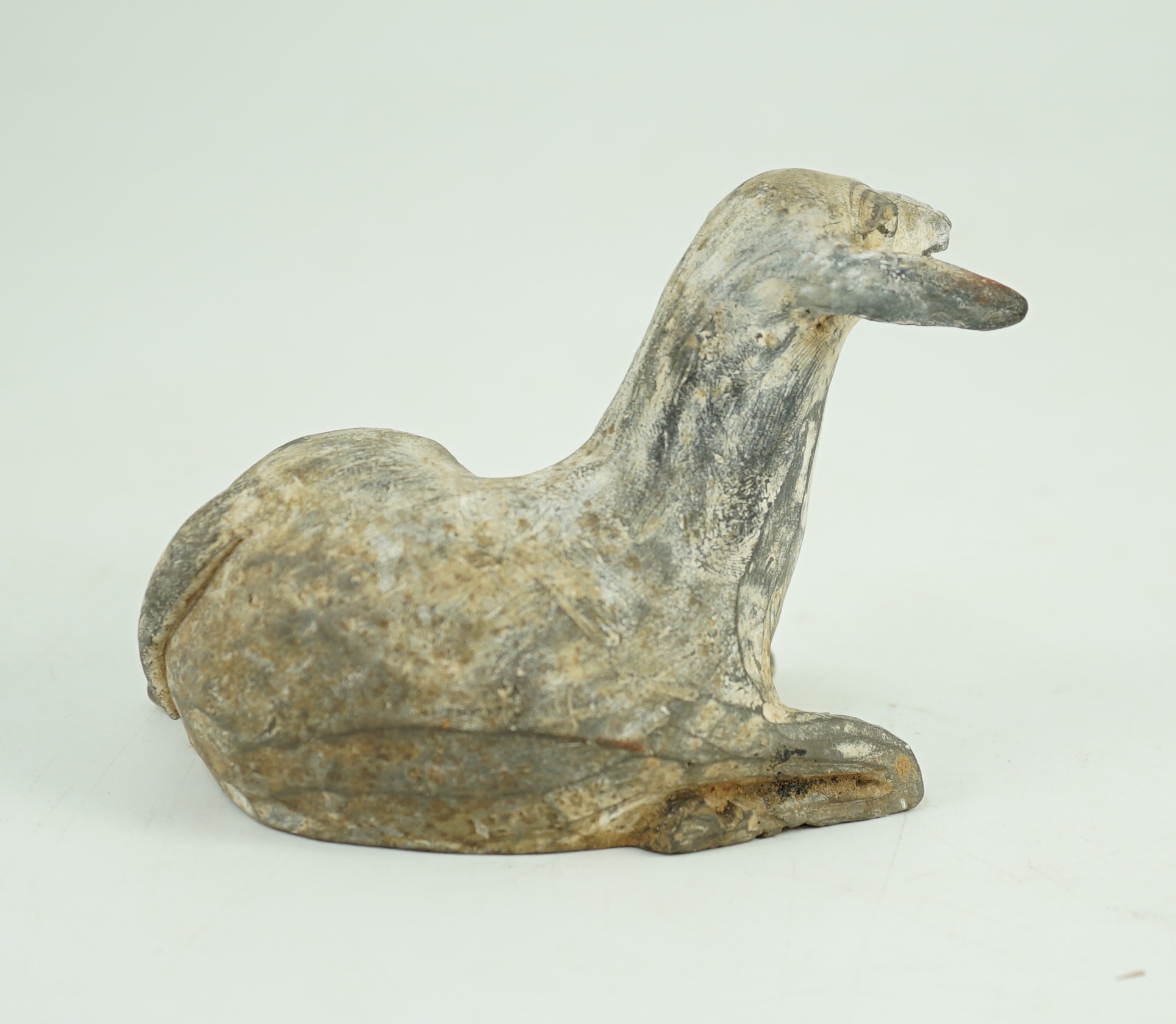 A Chinese painted grey pottery model of a recumbent sheep, Han dynasty, 10.2 cm long, One ear re-glued